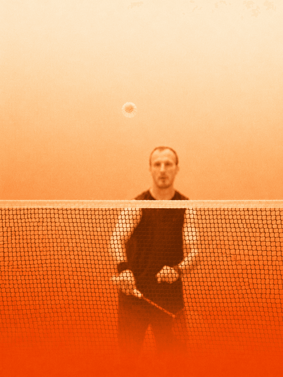 A player at the net during training, seen through the badminton net