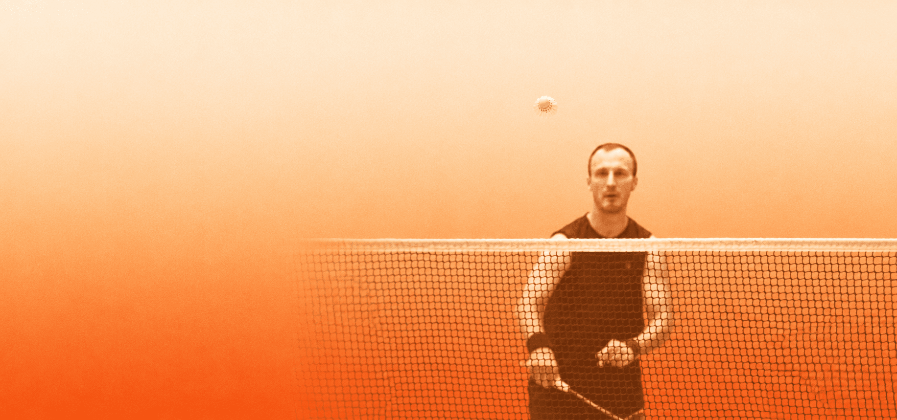 A player at the net during training, seen through the badminton net